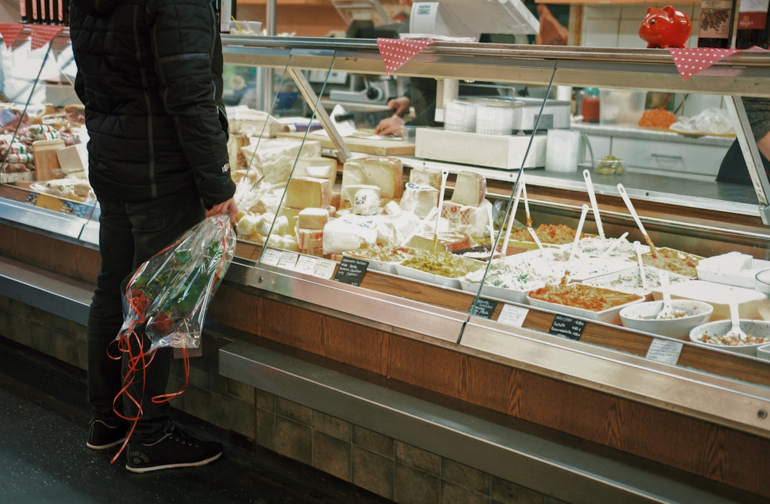 man with bouquet of roses standing in front of food display