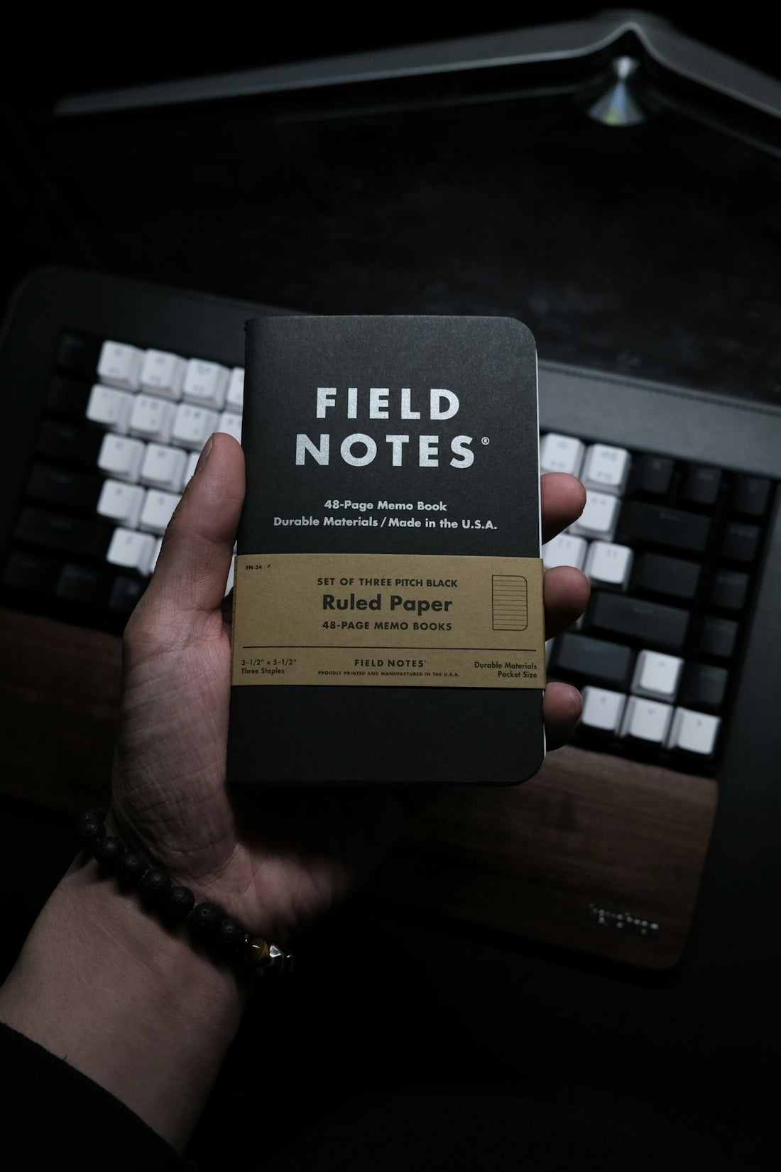 a person holding a book in front of a keyboard