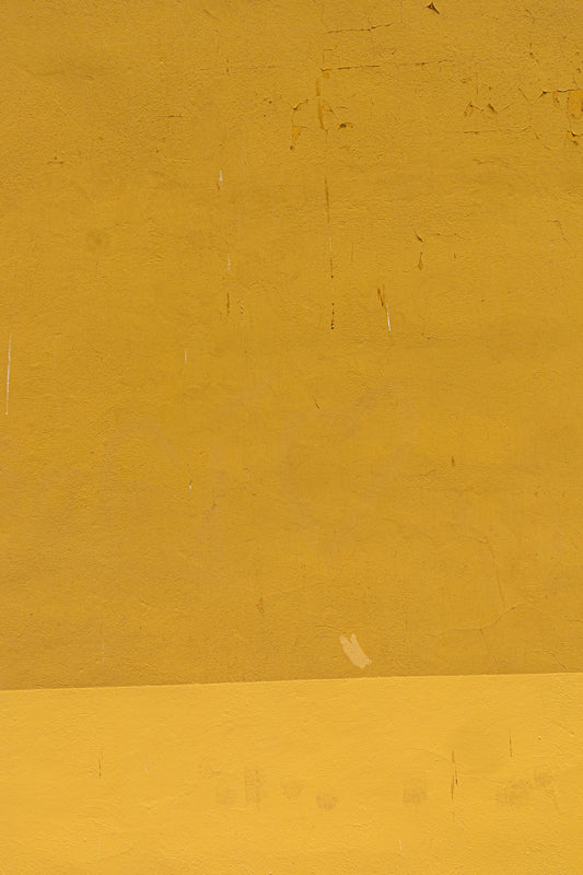 a man riding a skateboard down a street next to a yellow wall