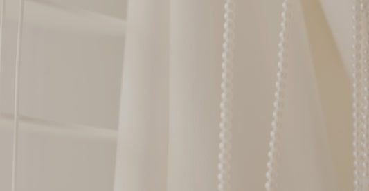 a close up of a white curtain with beads hanging from it