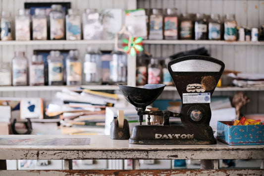 Vintage scale on a cluttered counter with shelves.
